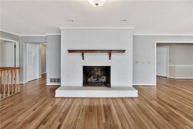 unfurnished living room featuring baseboards, visible vents, crown molding, and wood finished floors