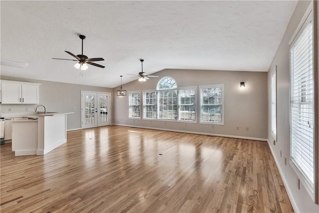 unfurnished living room featuring baseboards, vaulted ceiling, light wood-style flooring, and a ceiling fan