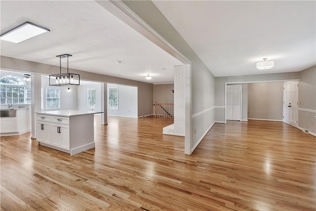 interior space with white cabinets, a healthy amount of sunlight, light wood-type flooring, and open floor plan