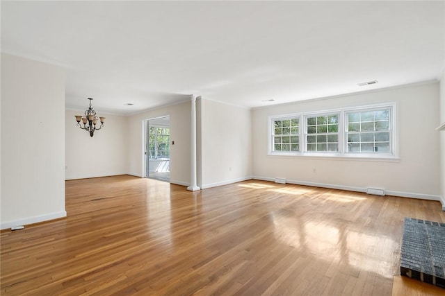 unfurnished room featuring crown molding, an inviting chandelier, baseboards, visible vents, and wood finished floors