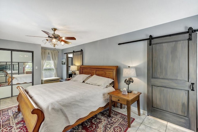 bedroom featuring a barn door, ceiling fan, and light tile patterned floors