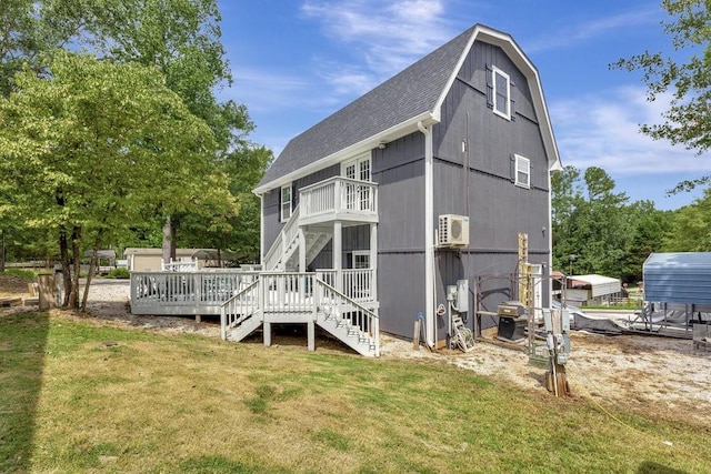 back of house with stairs, a gambrel roof, roof with shingles, a wall unit AC, and a yard