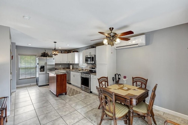 kitchen featuring white cabinets, ceiling fan, stainless steel appliances, a kitchen island, and an AC wall unit