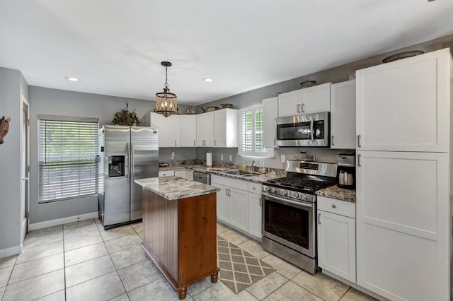 kitchen featuring a sink, white cabinetry, light stone countertops, a center island, and stainless steel appliances