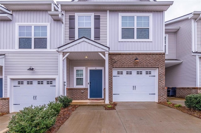 multi unit property featuring an attached garage, concrete driveway, board and batten siding, and brick siding