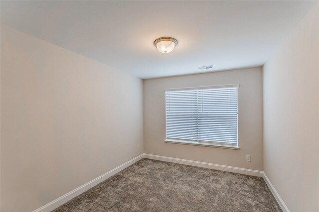 carpeted empty room featuring baseboards and visible vents