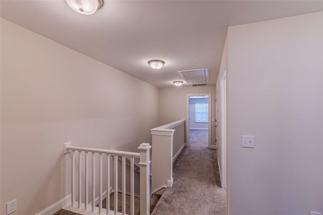 corridor featuring baseboards, carpet floors, an upstairs landing, and attic access