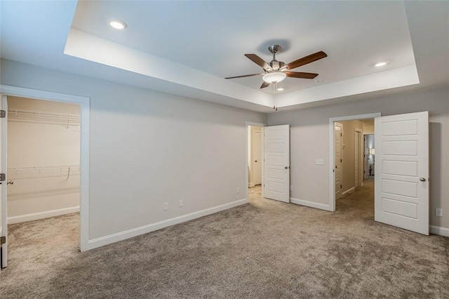 unfurnished bedroom featuring carpet floors, a tray ceiling, baseboards, and recessed lighting