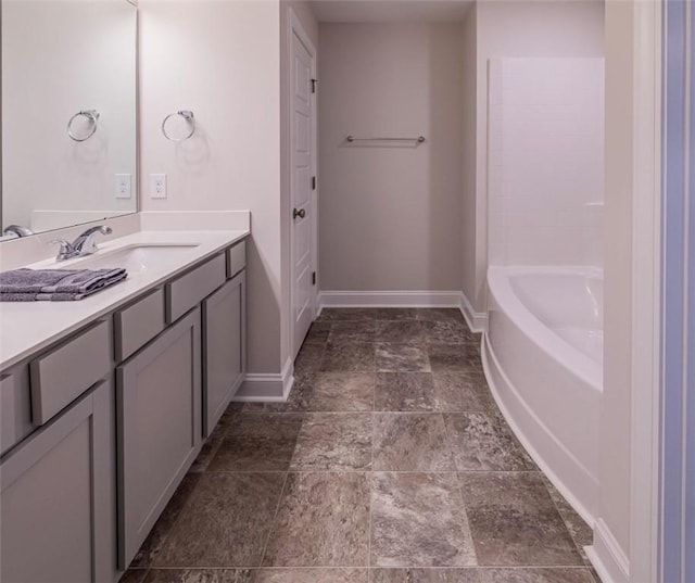 bathroom with a tub, vanity, and baseboards
