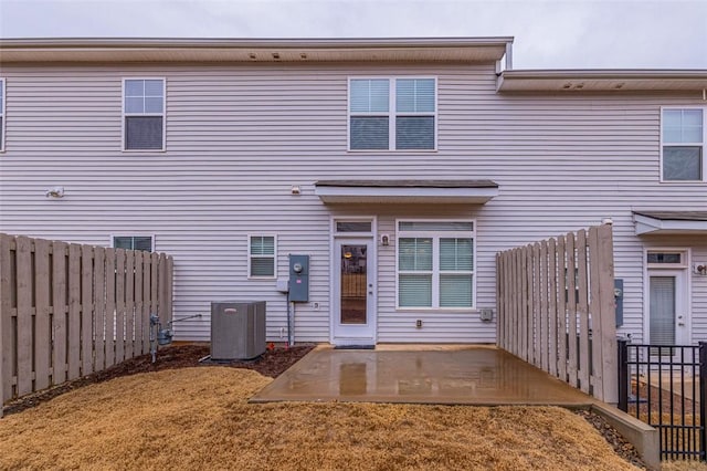 back of property featuring a fenced backyard, a patio area, central AC, and a yard