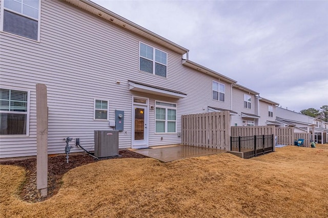 back of property with central AC unit, a lawn, fence, and a patio