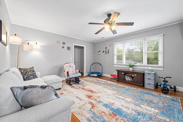 living room featuring ceiling fan, baseboards, crown molding, and wood finished floors