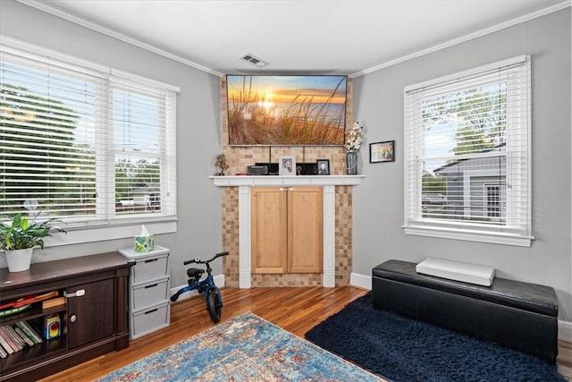 living area with crown molding, visible vents, baseboards, and wood finished floors