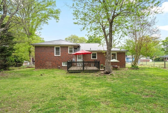 back of house with a deck, metal roof, a lawn, a fenced backyard, and brick siding