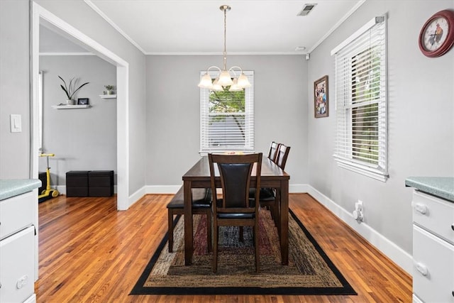 dining space featuring light wood-style floors, a notable chandelier, ornamental molding, and visible vents