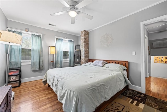 bedroom with visible vents, baseboards, ornamental molding, and light wood-style flooring