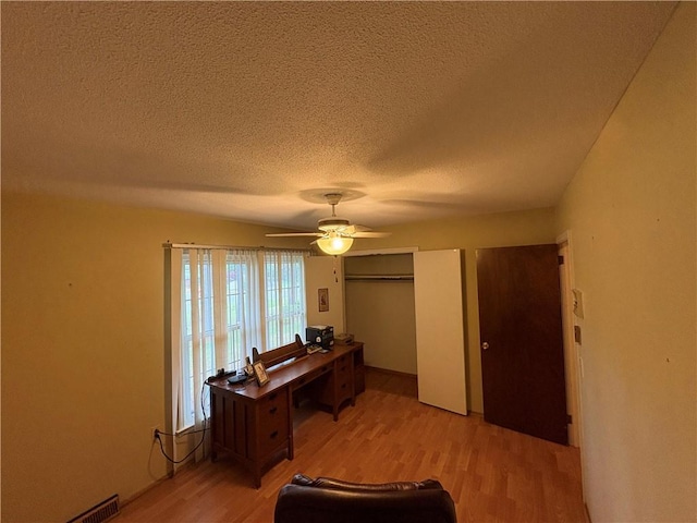 office area with light wood-style flooring, visible vents, ceiling fan, and a textured ceiling