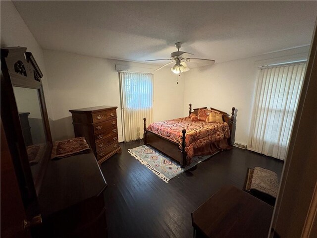 bedroom with multiple windows, visible vents, ceiling fan, and dark wood-style flooring