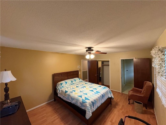 bedroom featuring a closet, a textured ceiling, baseboards, and light wood-type flooring