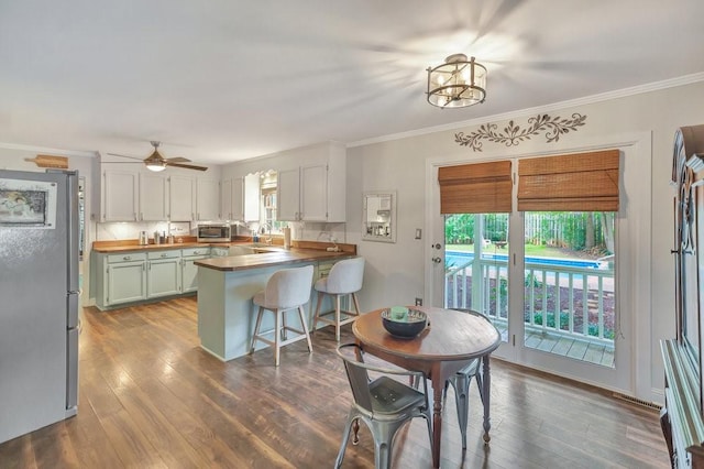 224 Regency Cir, Anderson, SC 29625 - kitchen featuring dark wood-type flooring, ornamental molding, a peninsula, and appliances with stainless steel finishes