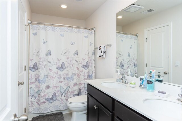 full bath with double vanity, visible vents, toilet, and a sink