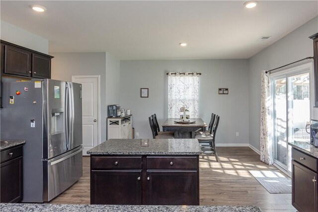 kitchen featuring dark brown cabinets, recessed lighting, light wood-style floors, stone countertops, and stainless steel fridge with ice dispenser