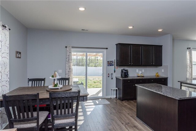 kitchen with dark stone countertops, visible vents, recessed lighting, wood finished floors, and a kitchen island