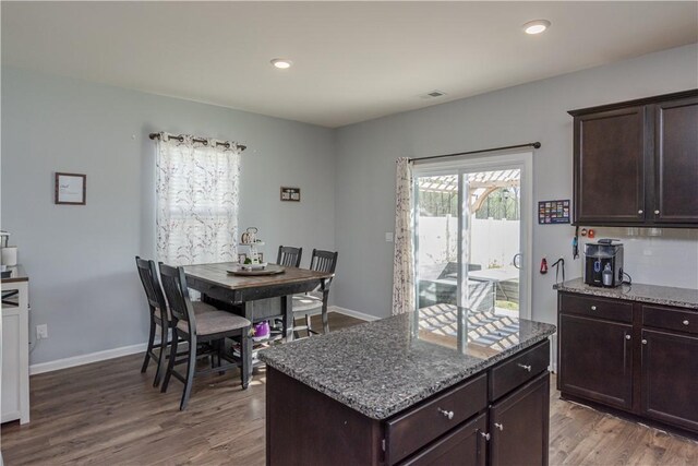 kitchen featuring visible vents, wood finished floors, stone countertops, and dark brown cabinetry