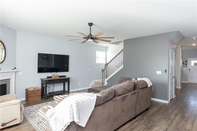 living room featuring stairway, wood finished floors, baseboards, and ceiling fan