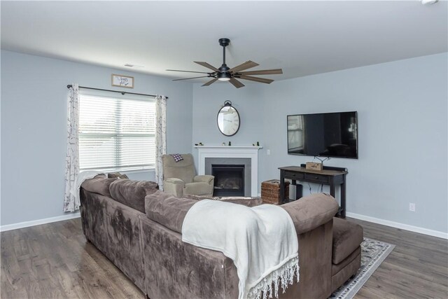 living room with wood finished floors, visible vents, a ceiling fan, baseboards, and a fireplace