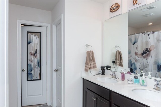 bathroom with double vanity, visible vents, and a sink