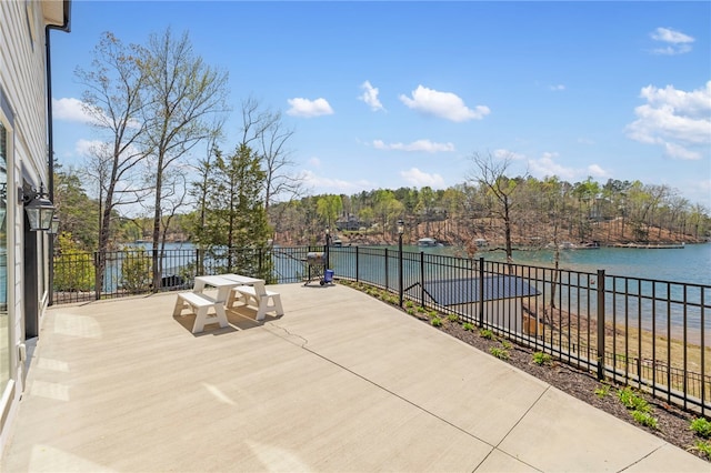view of patio featuring outdoor dining space, a water view, and fence