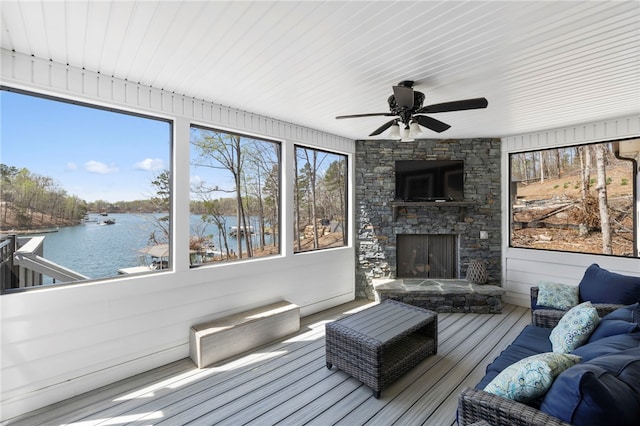 sunroom / solarium featuring a ceiling fan, an outdoor living space with a fireplace, and plenty of natural light