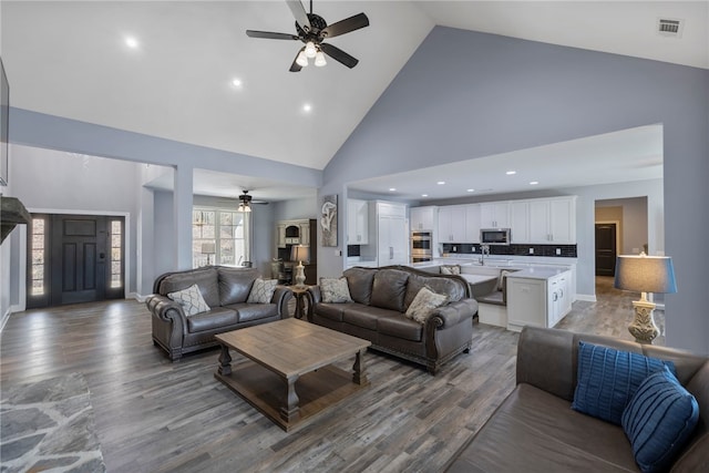 living area with high vaulted ceiling, baseboards, visible vents, ceiling fan, and wood finished floors
