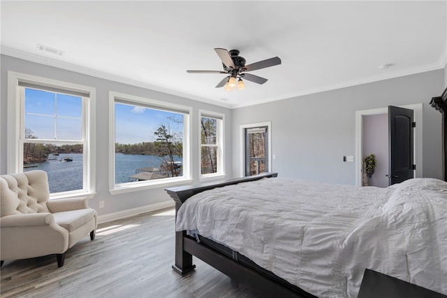 bedroom with wood finished floors, crown molding, multiple windows, and visible vents