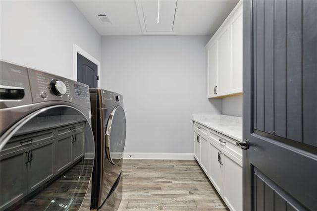 washroom with visible vents, baseboards, light wood-type flooring, washer and dryer, and cabinet space