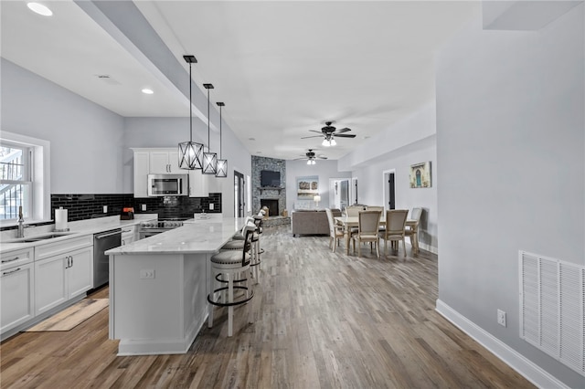 kitchen with open floor plan, white cabinetry, ceiling fan, visible vents, and appliances with stainless steel finishes