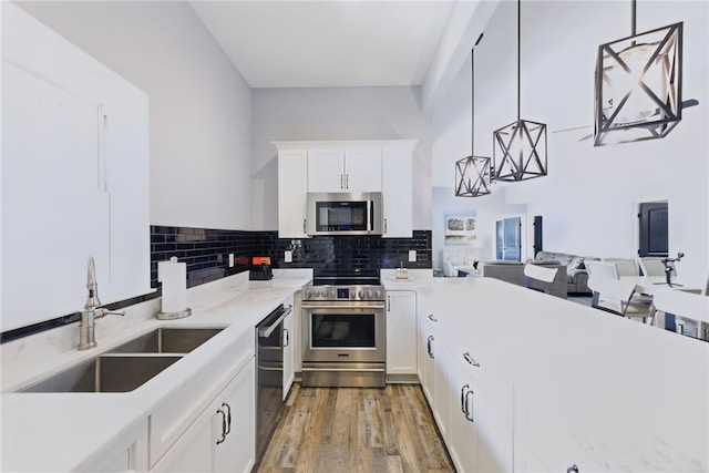 kitchen featuring a sink, appliances with stainless steel finishes, light wood-style flooring, white cabinets, and decorative backsplash