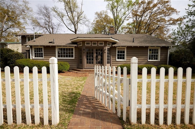 back of house featuring a chimney, a fenced front yard, and french doors