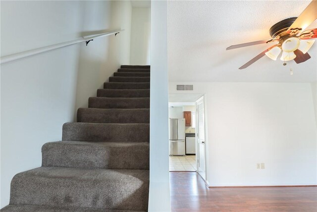 stairs featuring visible vents, wood finished floors, and a ceiling fan