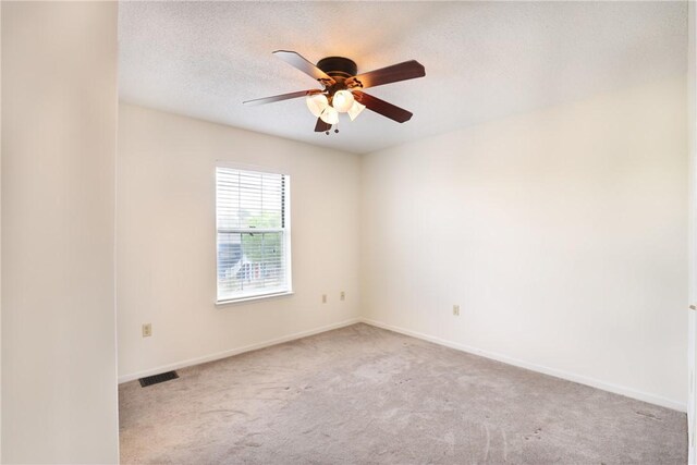 carpeted empty room with a textured ceiling, baseboards, ceiling fan, and visible vents
