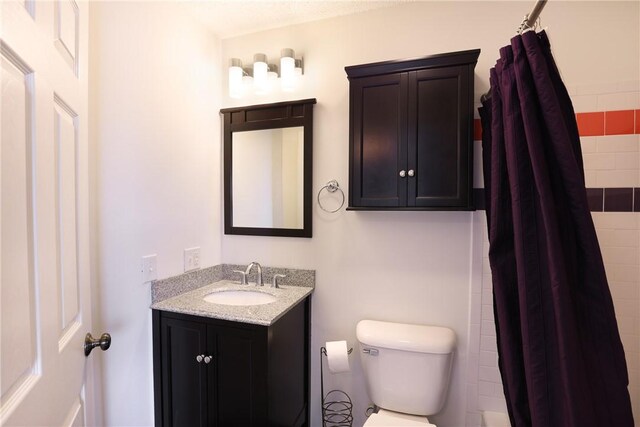 bathroom featuring a tile shower, toilet, and vanity