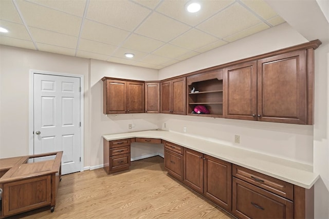 unfurnished office with a paneled ceiling, light wood-style flooring, built in desk, and recessed lighting