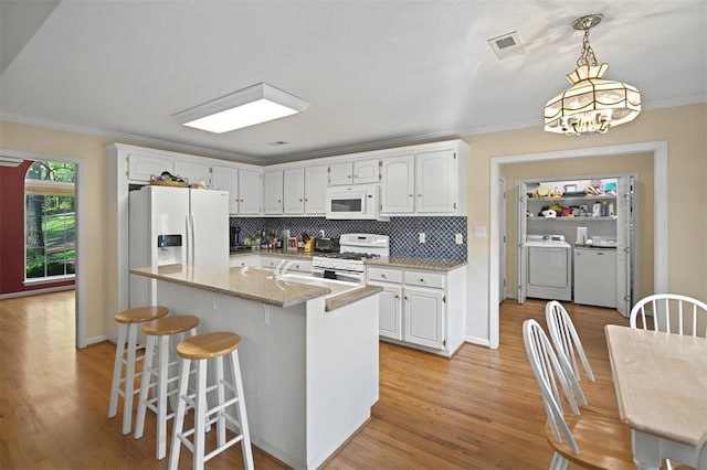 kitchen featuring washer and dryer, white appliances, visible vents, and white cabinets