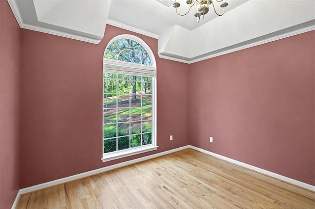 empty room featuring a chandelier, baseboards, ornamental molding, and light wood-style floors