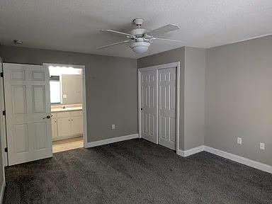 235 Lookover Dr, Anderson, SC 29621 - unfurnished bedroom with dark carpet, a closet, connected bathroom, and ceiling fan