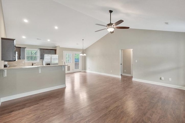 unfurnished living room featuring vaulted ceiling, recessed lighting, baseboards, a ceiling fan, and wood finished floors