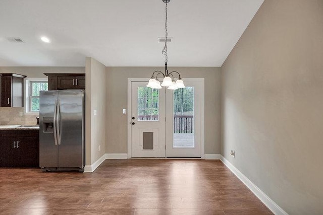 doorway to outside featuring visible vents, a chandelier, baseboards, dark wood-type flooring, and a sink