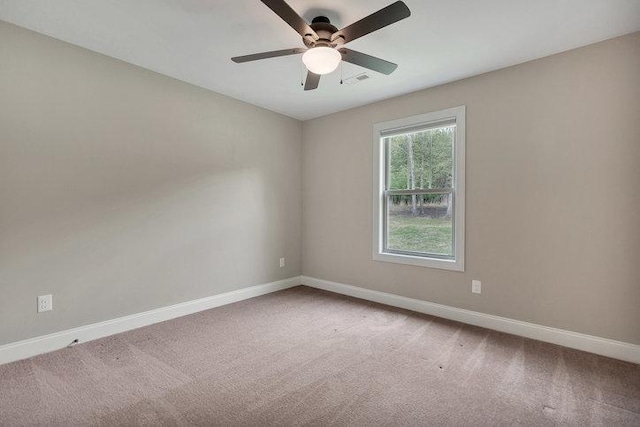 spare room featuring baseboards, a ceiling fan, and light carpet