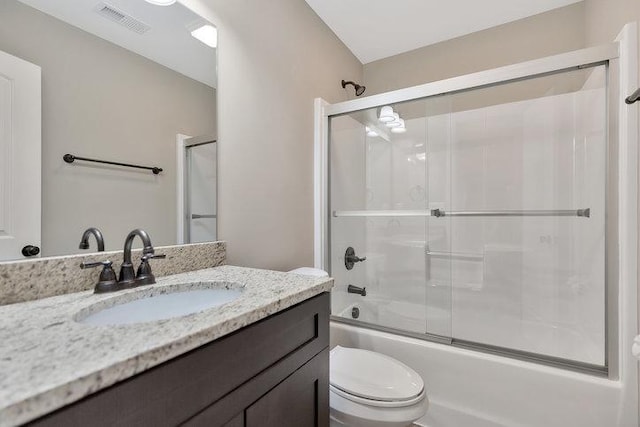 bathroom with visible vents, toilet, vanity, and shower / bath combination with glass door